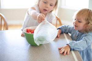 Little girls taking silicone bowl cover off form a bowl with watermelon