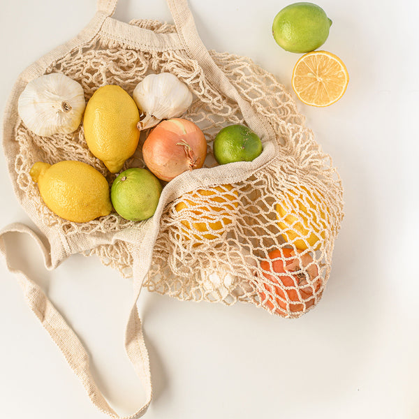 Reusable bag for groceries 100% cotton and natural with some vegetables and fruits.